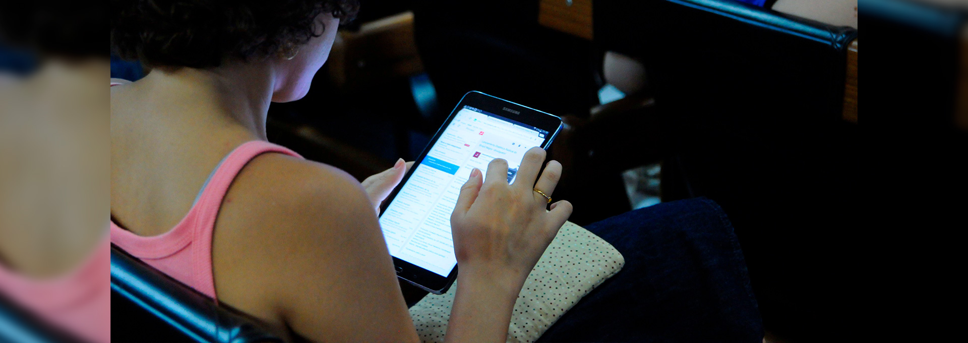 Grupo da Unicamp investiga fake news do Coronavírus foto mostra mulher sentada em uma cadeira, de costas para a câmera, manuseando um tablet