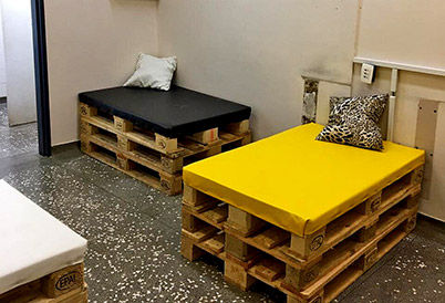 foto mostra duas camas feitas com pallets empilhados e colchonetes por cima