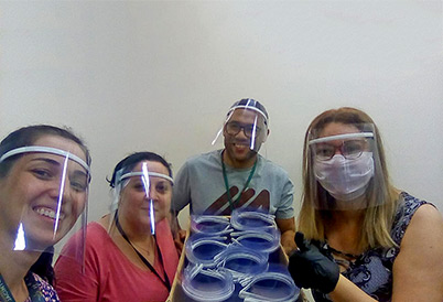 HC recebeu 500 itens; Vizinhos de condomínio também doaram equipamentos ao Hospital Municipal Mário Gatti Foto mostra moradores do condomínio usando os protetores faciais e segurando uma caixa com os que serão doados