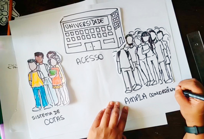 audiodescrição: fotografia colorida mostra um cartaz em que estão sendo desenhados em uma cartolina a universidade e pessoas representando candidatos ao vestibular unicamp