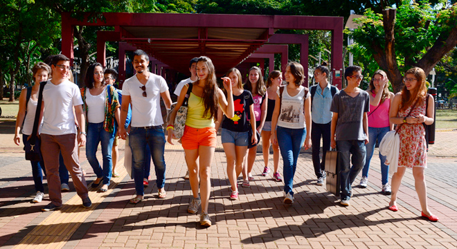 Dezenas de estudantes caminham juntos em frente ao Restaurante Universitário