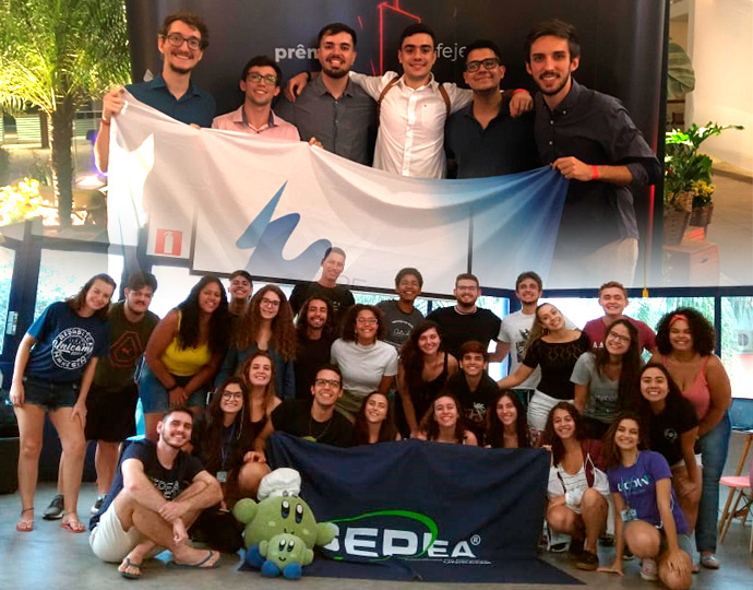 O GEPEA e a 3E foram fundadas em 1990 e estão também entre as mais antigas do Brasil Foto de dezenas de estudantes que compõem as empresas juniores com as bandeiras de suas respectivas empresas