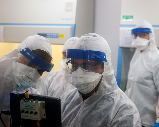 foto mostra pesquisadores dentro de um laboratório usando roupas de proteção