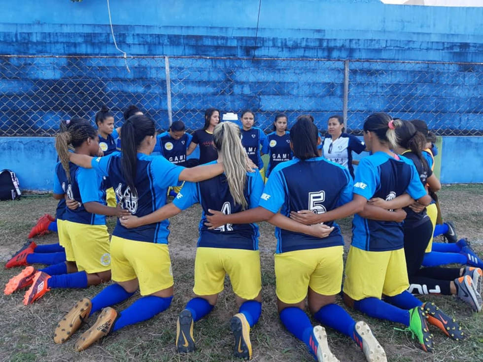 foto mostra time de futebol feminino do gami ajoelhadas fazendo oração