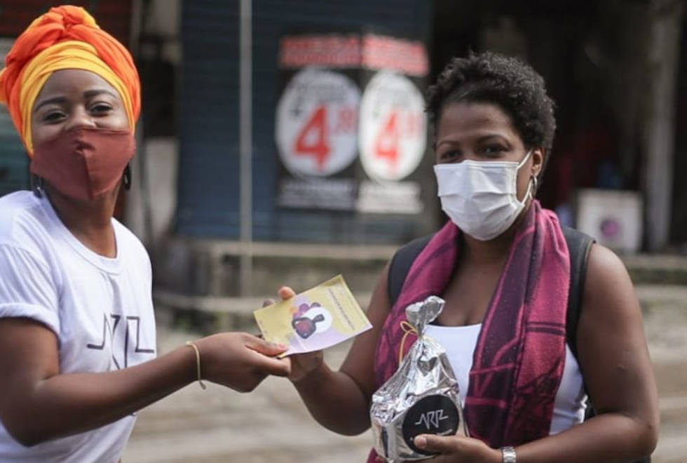Na segunda etapa, 44 tablets foram comprados a crianças da Rocinha foto mostra voluntária da rocinha resiste entregando panfleto à moradora