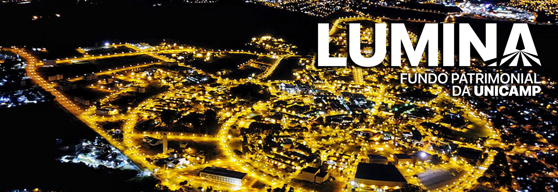 foto mostra vista aérea noturna da unicamp com o logo do fundo lumina no canto superior direito