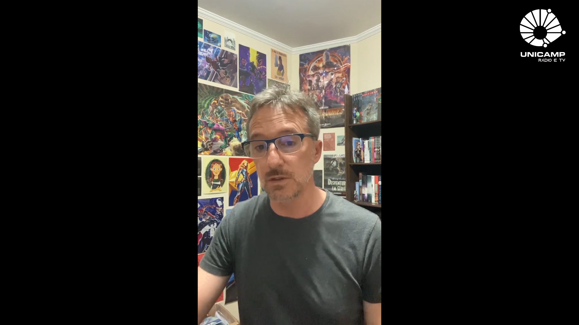 imagem mostra professor luiz carlos dias em uma sala com posteres de filmes
