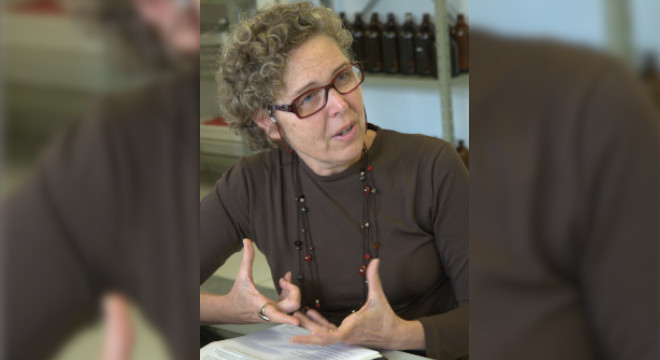 Gisela Umbuzeiro é reconhecida como uma das mulheres pioneiras na toxicologia audiodescrição: fotografia colorida da professora gisela umbuzeiro, ela está gestilando e sentada em frente a uma mesa branca