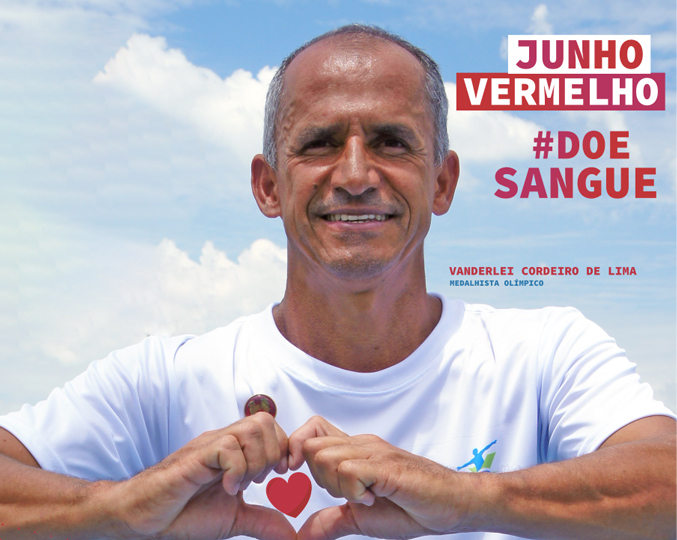 Neste ano, ação lembra da importância das práticas esportivas para manutenção da saúde foto mostra o maratonista vanderlei cordeiro fazendo um coração com as mãos e o texto "junho vermelho doe sangue"