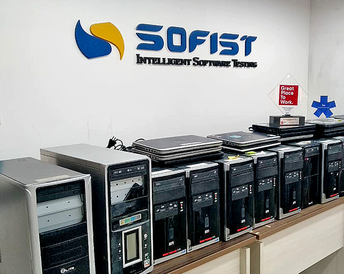 CompSocial já arrecadou mais de 500 equipamentos audiodescrição: fotografia colorida de computadores sobre uma mesa; ao fundo, a logo da empresa sofist