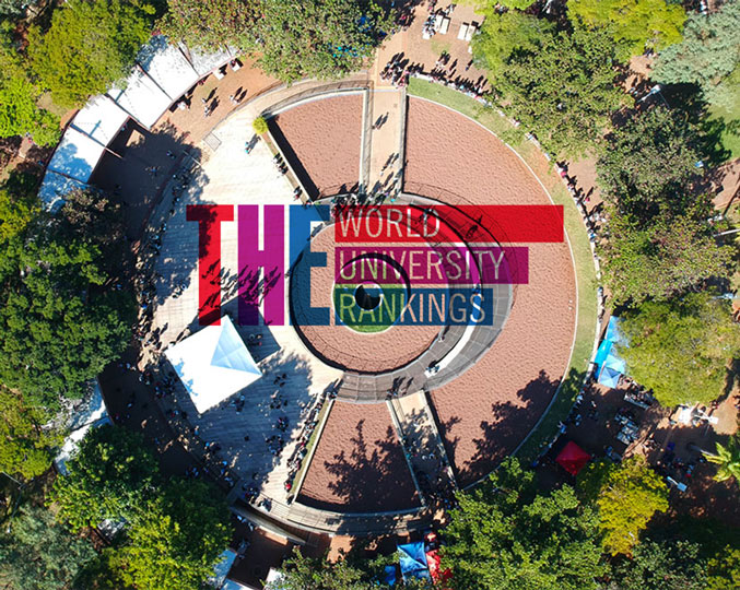 audiodescrição: fotografia colorida de imagem aérea do campus e sobreposta a ela há o logo do times higher education
