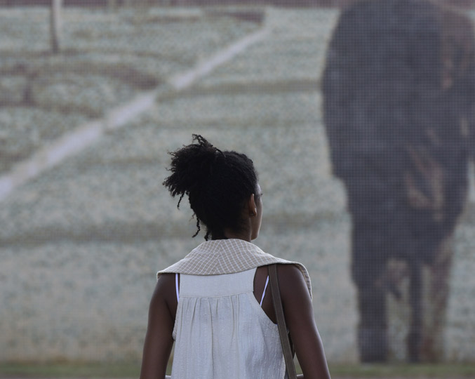audiodescrição: fotografia colorida mostra uma estudante de costas caminhando, ela está no campus de campinas da unicamp 
