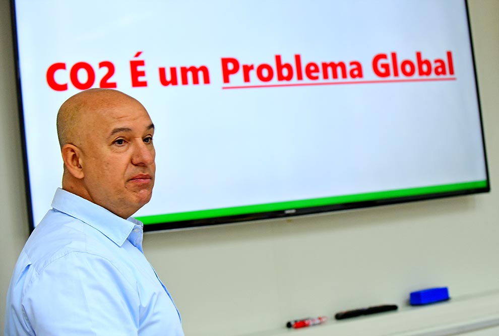 foto mostra professor gonçalo pereira em uma apresentação. na tela ao fundo, há a frase "co2 é um problema global"