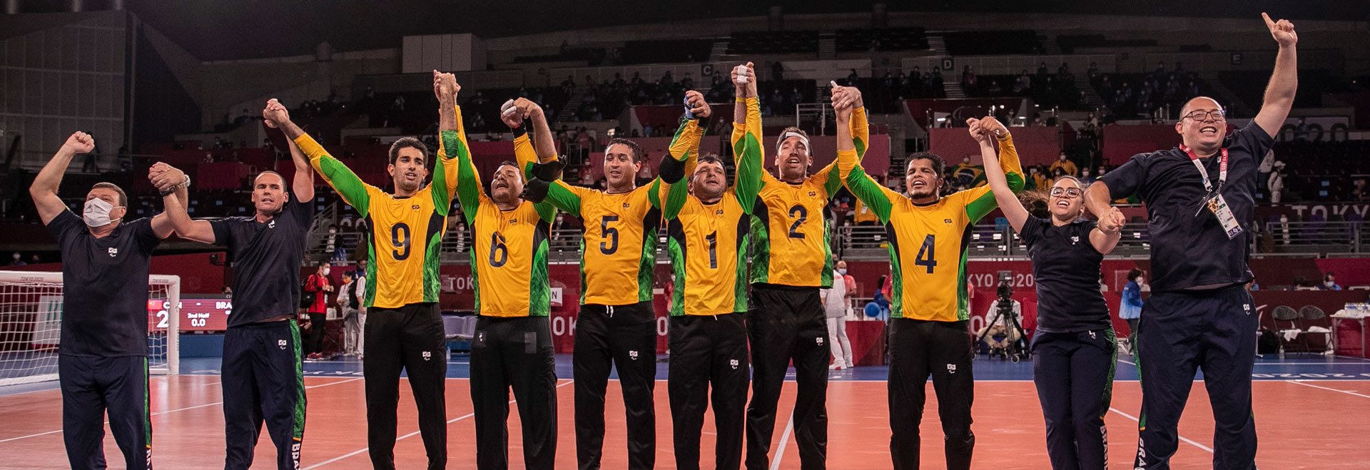 foto mostra time brasileiro de goalball posicionado em linha, com as mãos levantadas, comemorando vitória