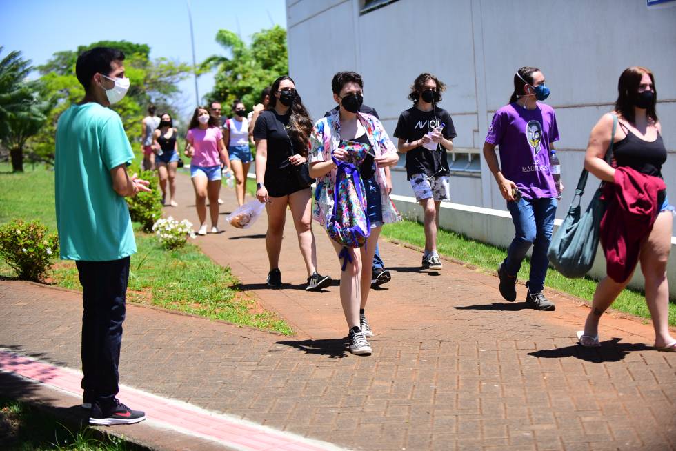 audiodescrição: fotografia colorida mostra estudantes caminhando ao ar livre; um monitor do vestibular acompanha o movimento