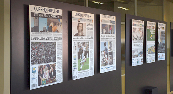Exposição "Correio Popular 95 anos" está aberta à visitação audiodescrição: fotografia colorida de paineis com as capas do jornal correio popular