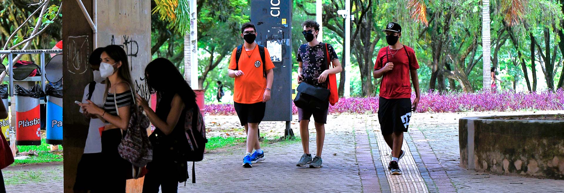 audiodescrição: fotografia colorida de estudantes caminhando pelo campus