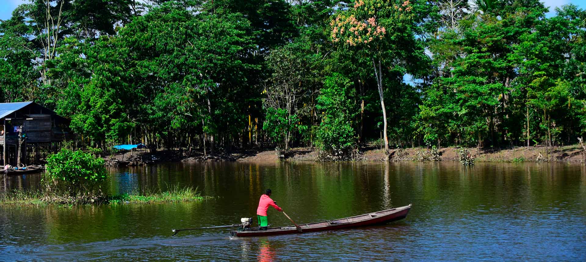 Cenário na Comunidade Umariaçu II, em Tabatinga: relação dos povos originários com o ambiente deve ser um aprendizado (Foto: Antonio Scarpinetti) audiodescrição: um lago ao lado da floresta amazônica. Um barco com pescadores.
