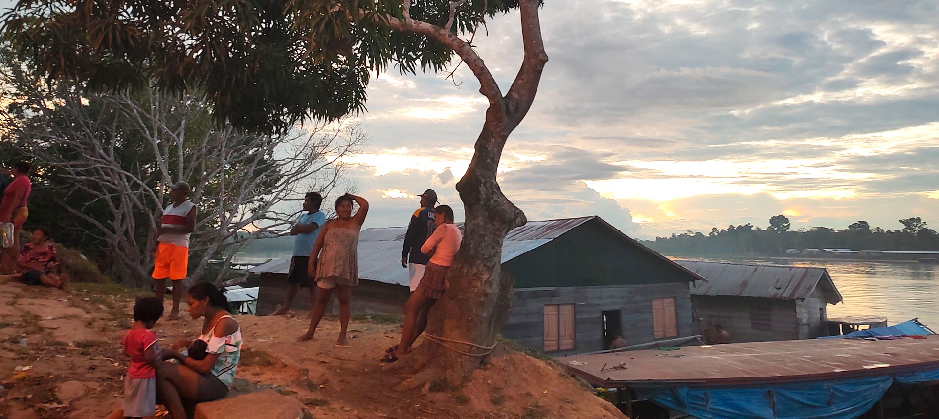 Base abandonada da Funai às margens do rio Javari, em Atalaia do Norte: dossiê expõe desmonte do órgão pelo governo Bolsonaro audiodescrição; fotografia colorida de indígenas na beira do rio javari; às margens, há uma construção de madeira abandonada