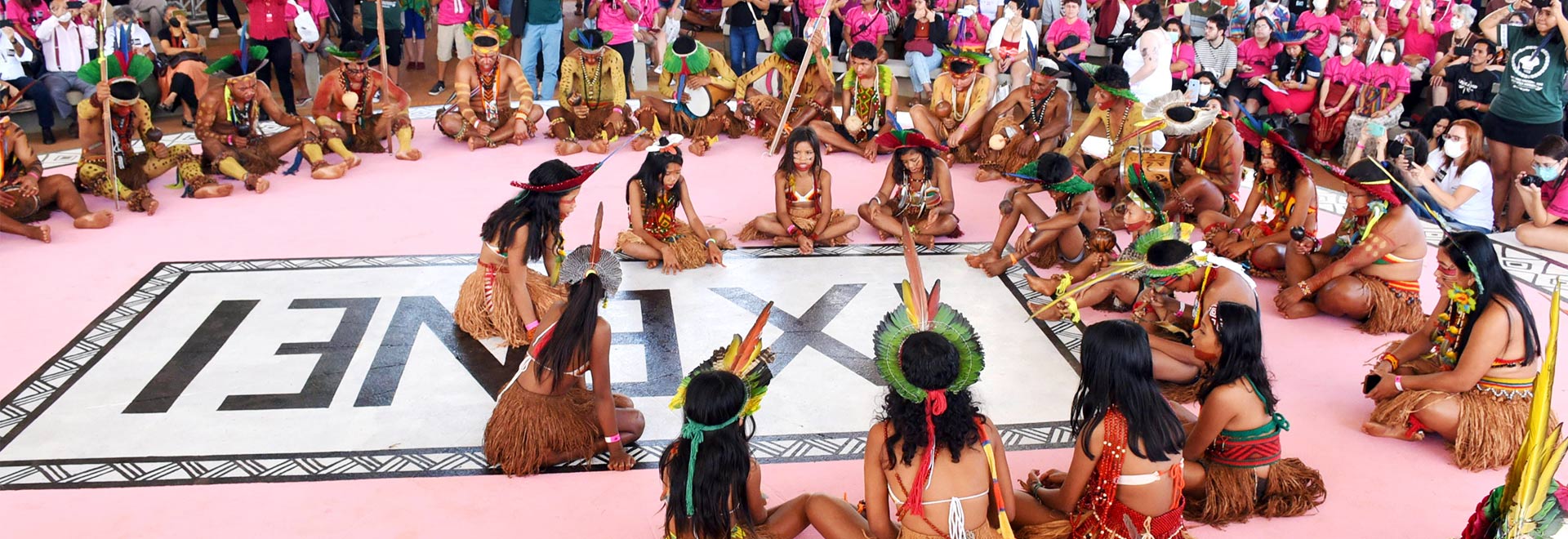 IX Encontro Nacional dos Estudantes Indígenas ocorre entre 26 e 29 de julho na Unicamp audiodescrição: fotografia colorida de grupo indígena no palco do IX ENEI