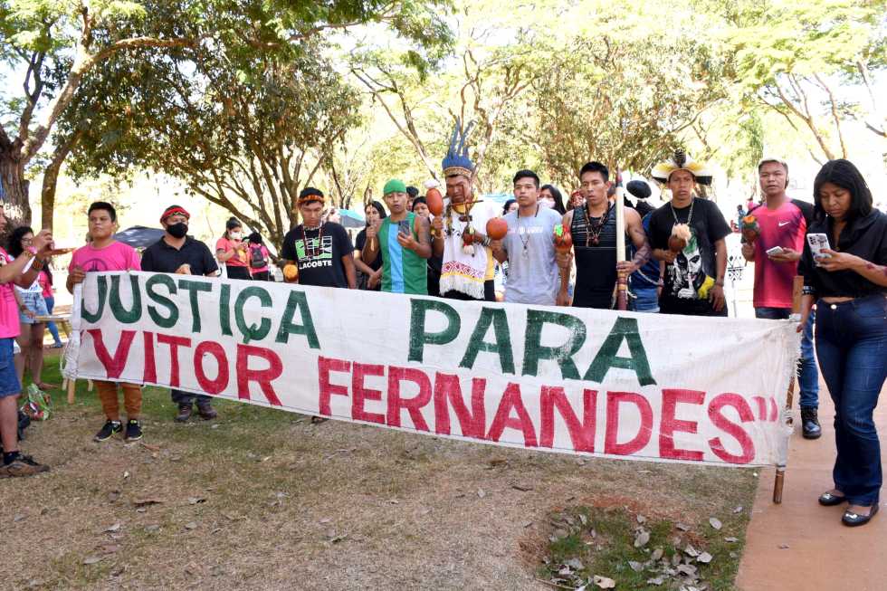 audiodescrição: fotografia colorida mostra estudantes indígenas segurando um cartaz com os dizeres justiça para "vitor fernandes"