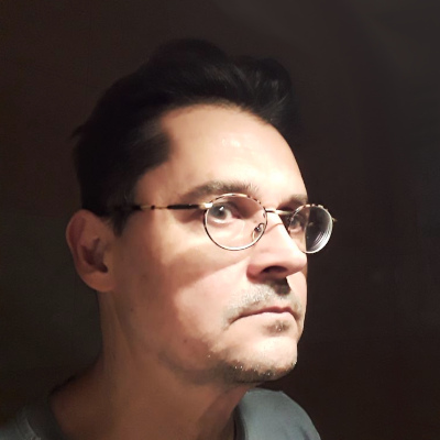 audiodescrição: imagem colorida, de perfil, Alexandre veste camiseta cinza, usa óculos