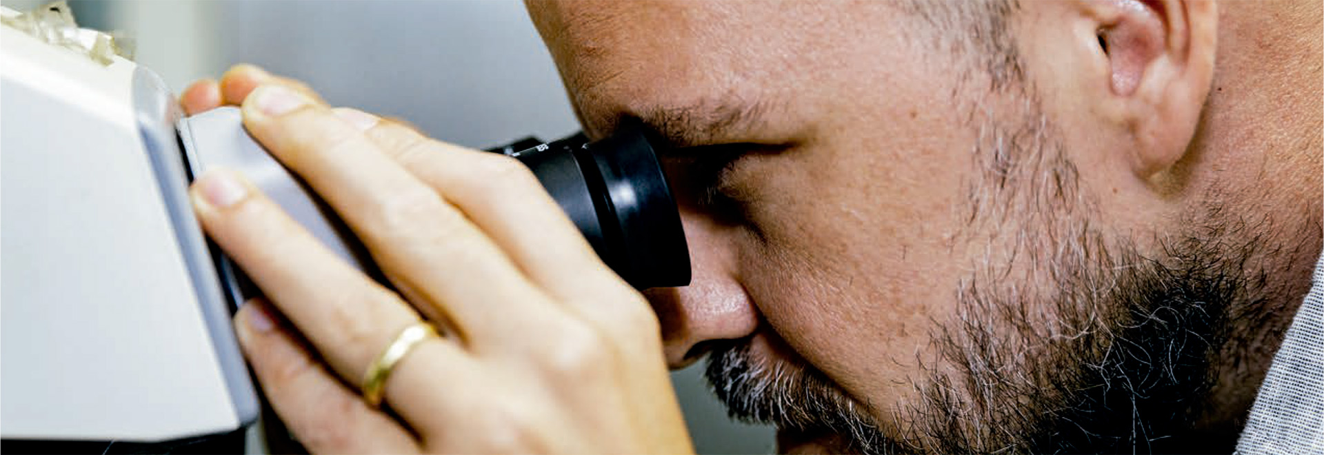 Audiodescrição (AD): Foto mostra um homem olhando em um microscópio. Imagem 1 de 1