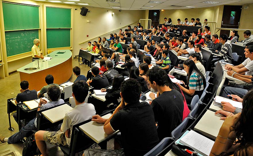 Foto de um grupo de alunos em uma sala de aula com um professor à frente