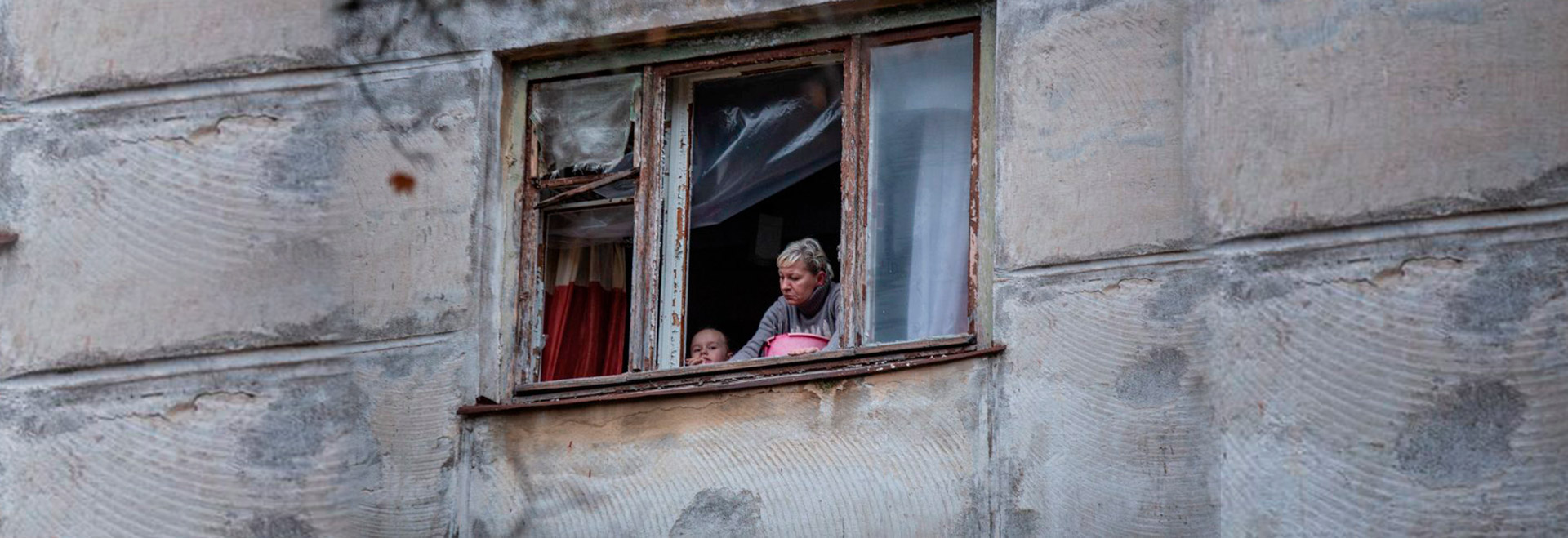 Mãe e filho inspecionam sua janela quebrada depois que o projétil caiu meia hora atrás perto de sua casa, Kherson-novembro 2022 (Foto: Oleksandr Ratushniak / PNUD Ucrânia)