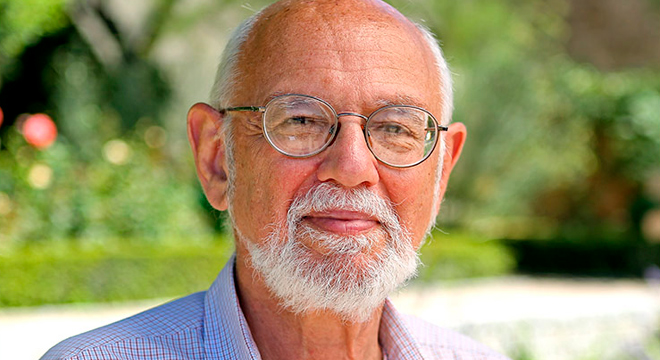 O professor norte-americano David Konstan, da New York University, é reconhecido há décadas por seu trabalho nos Estudos Clássicos, em áreas como Teatro Antigo, História das Emoções, História do Perdão e História das Religiões Audiodescrição. Foto: acervo pessoal. Em área externa, imagem frontal à curta distância de homem com olhar voltado para a câmera fotográfica, com braços baixados e que expressa sorriso tímido. Ele usa óculos e veste camisa social quadriculada com fundo branco e finas riscas em vermelho. Ao fundo, imagem desfocada de área verde. Imagem 1 de 1
