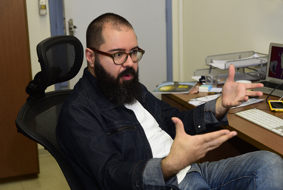 Eduardo Valle, docente da Faculdade de Engenharia Elétrica e de Computação (FEEC) da Unicamp, responsável pelo projeto do Melanoma A galeria apresenta imagens do docente da Faculdade de Engenharia Elétrica e de Computação (FEEC) da Unicamp, Eduardo Valle, em sua sala de trabalho. Para acessá-la, tecle enter. Descritivo: Em sala de trabalho, homem sentado em moderna cadeira de escritório, com as pernas cruzadas, e gesticulando com os braços, deixando-os erguidos para frente, na altura do peito, e as mãos abertas, uma de frente para outra, como se apontasse para algo à frente. Ele usa óculos, e veste calça e jaqueta jeans. Imagem 1 de 3.