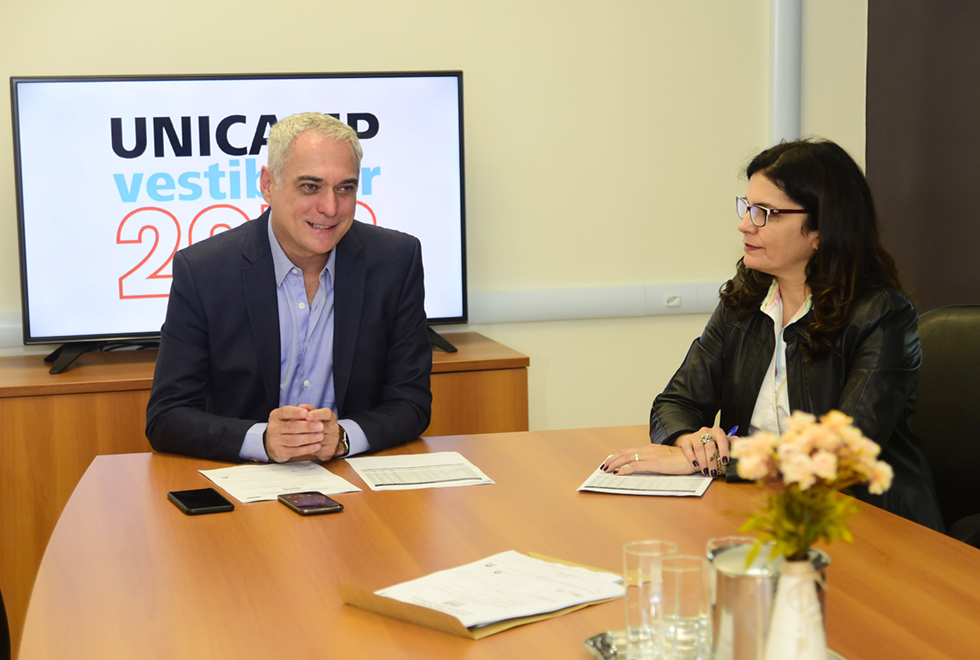 O coordenador executivo da Comissão Permanente para os Vestibulares da Unicamp (Comvest), José Alves de Freitas Neto, e a coordenadora acadêmica da Comvest, Márcia Mendonça, durante coletiva de imprensa do Vestibular Unicamp 2018 A galeria traz coletiva de imprensa com coordenadores da Comissão Permanente para os Vestibulares (Comvest). Para acessá-la, tecle enter. Audiodescrição: Em sala de reuniões, em imagem frontal, homem sentado em cadeira mantém os braços totalmente apoiados sobre uma mesa retangular de madeira, com as mãos unidas à frente. Ao lado dele, à direita, há uma mulher sentada em cadeira, com as mãos também apoiadas sobre essa mesa. Às costas dele há um monitor de lcd onde se lê Vestibular Unicamp 2018. Imagem 1 de 3