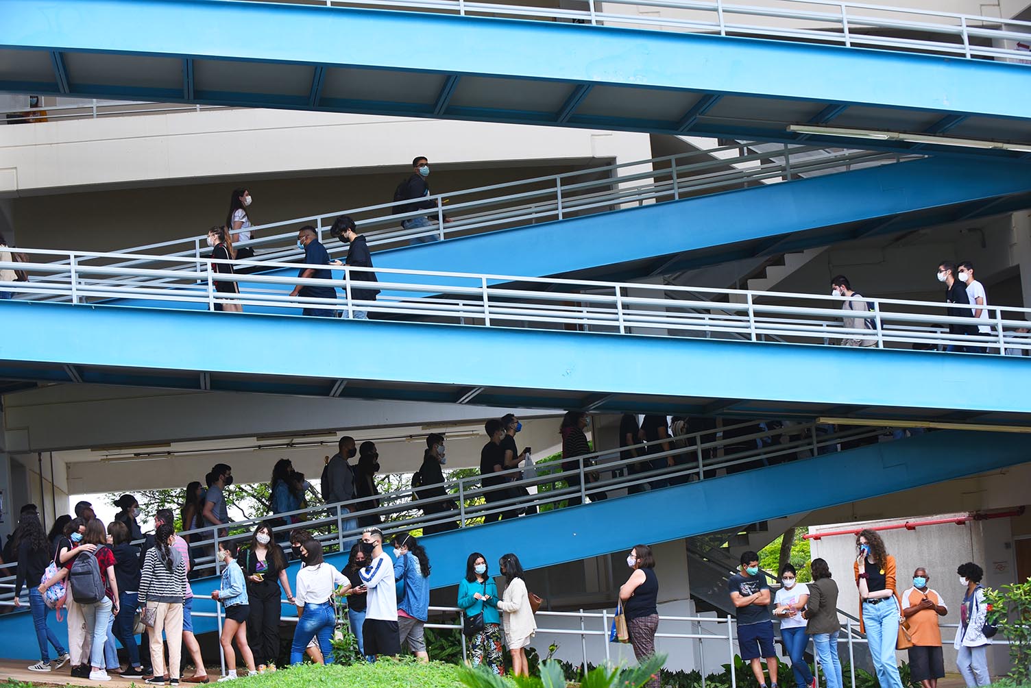 Entrada de candidatos para provas da segunda fase do Vestibular Unicamp 2022, na PUC-Campinas Audiodescrição: Em área externa, imagem panorâmica de ampla rampa de acesso construída com ferro, com 4 lances em zigue-zague, da direita para a esquerda. A rampa possui corrimãos laterais em toda sua extensa e é pintada em azul. Várias pessoas estão subindo pela rampa, principalmente no primeiro lance e na calçada de acesso. Imagem 6 de 20.