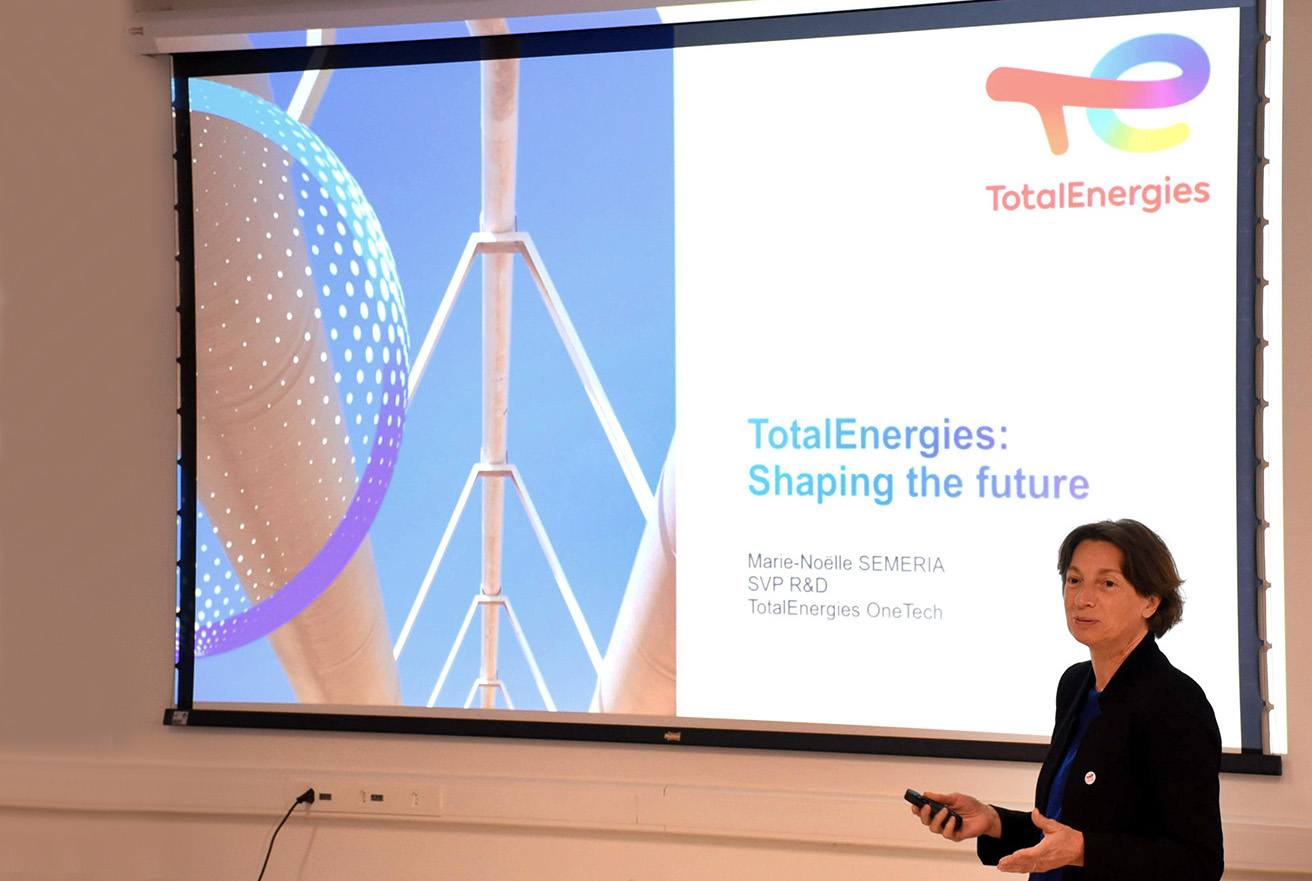 Marie-Noelle Semeria, diretora de Tecnologia da empresa francesa TotalEnergies – gigante global do setor de combustíveis, gás natural e energia, durante visita à Unicamp para avaliar parcerias de pesquisa em diversas áreas Audiodescrição: Em área interna, imagem em perspectiva e à média distância de mulher em pé, à direita na imagem, que fala e gesticula com as mãos, sem que segura uma caneta laser com a mão direita. Às costas dela, ao fundo de toda imagem, ampla tela de projeção de Data Show. Metade da tela, à esquerda, exibe imagem de dutos com o céu azul e meia circunferência em desenho estilizada. Na outra parte se lê TotalEnergies, em vermelho, com logo da empresa, e TotalEnergies: shaping the future. Imagem 1 de 9.