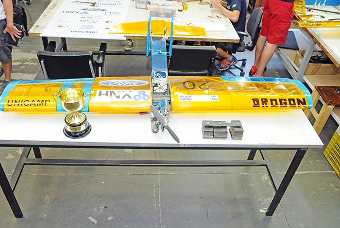 Avião Drogon e troféu conquistado na Competição SAE Brasil AeroDesign. Em destaque a carga de aço.
