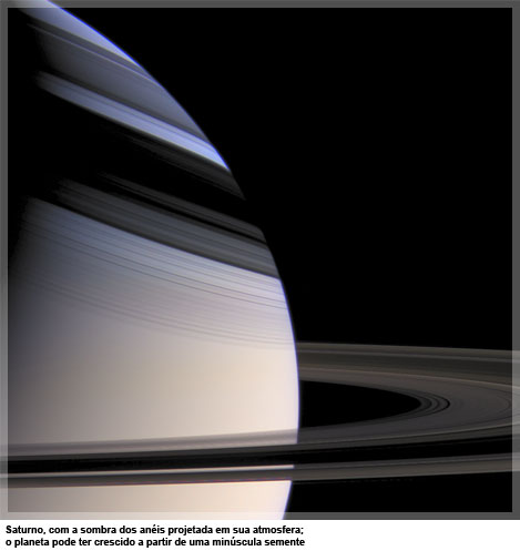 Saturno, com a sombra dos anéis projetada em sua atmosfera; o planeta pode ter crescido a partir de uma minúscula semente