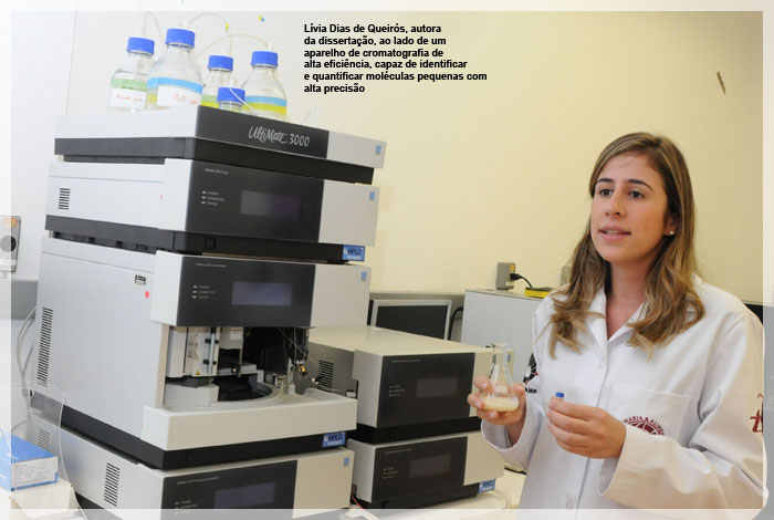 Lívia Dias de Queirós, autora da dissertação, ao lado de um aparelho de cromatografia de alta eficiência, capaz de identificar e quantificar moléculas pequenas com alta precisão