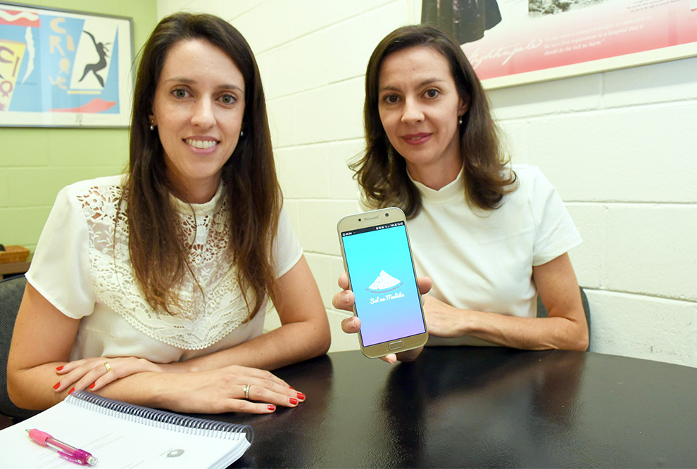 Milena Perin (à esq.), autora da pesquisa, com sua orientadora, a professora Marília Cornélio, e a imagem do aplicativo no celular: bons resultados