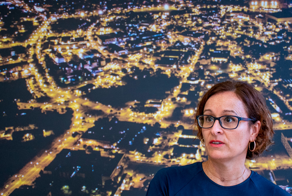 foto mostra a professora susana durão enquadrada no canto inferior direito com um painel do câmpus da unicamp ao fundo