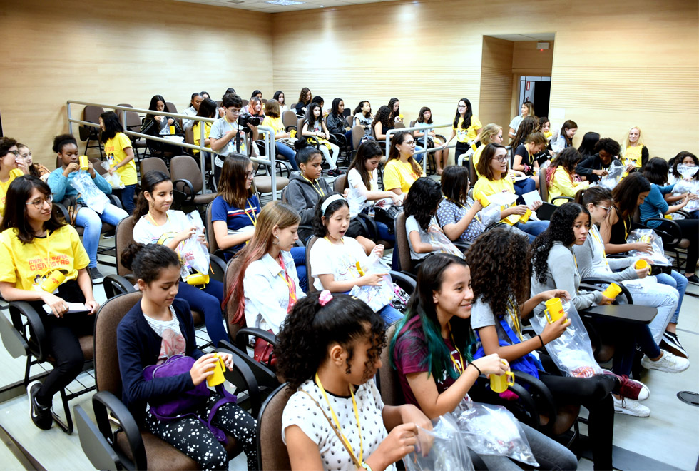 audiodescrição: fotografia colorida de plateia de jovens estudantes em auditório lotado