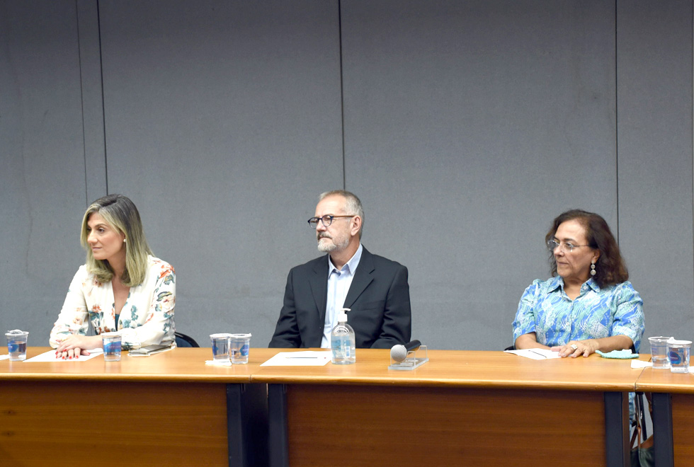 foto mostra calos etulain sentado à mesa com uma mulher à esquerda e uma à direita