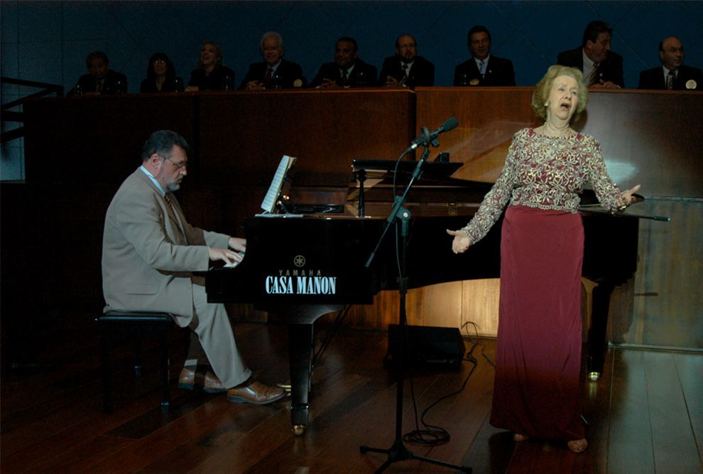 foto mostra niza tank cantando ao lado de um piano em um palco