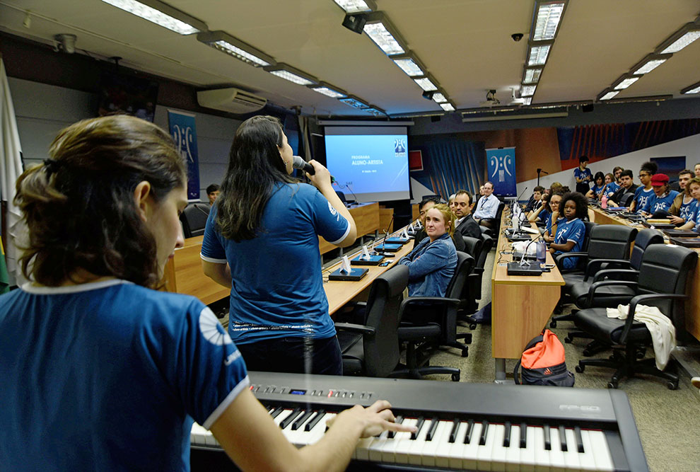 menina toca teclado em auditorio