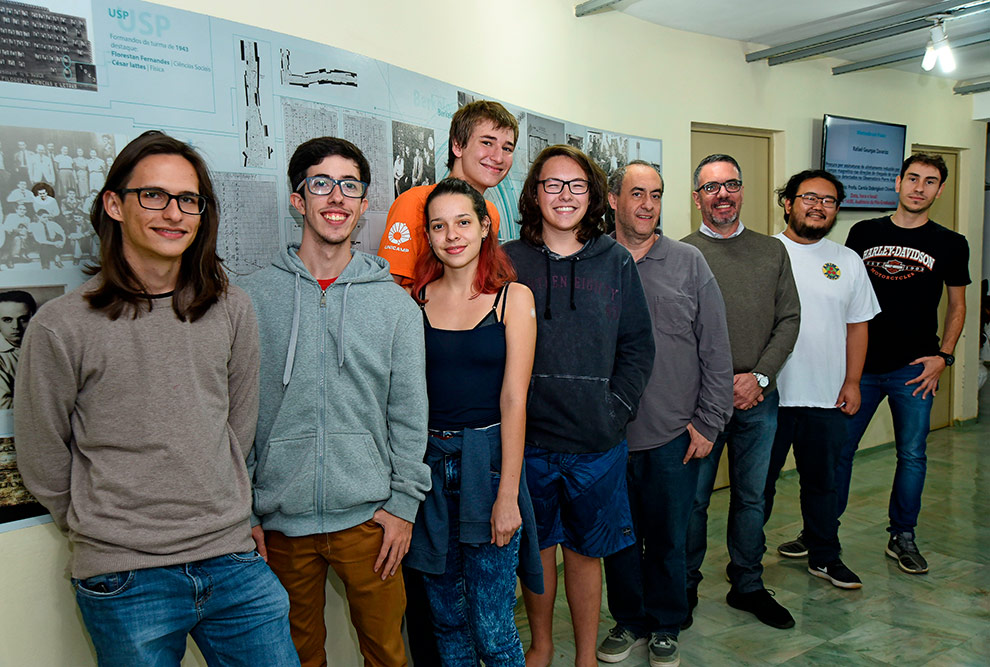 Grupo de estudantes e professores envolvidos no projeto posam para foto. Há  nove pessoas enfileiradas