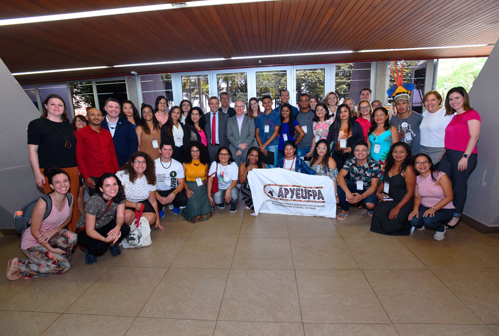 audiodescrição: fotografia colorida mostra cerca de 40 pessoas estão na foto, a maioria são jovens, estudantes indígenas, quilombolas e ribeirinhos e extrativistas da universidade federal do pará. também encontra-se o reitor da unicamp, pró-reitores da Unicamp e da universidade do pará e representantes do banco santander. alguns estão abaixados na foto, na primeira fileira, e seguram uma bandeira dos povos indígenas da universidade federal do pará.