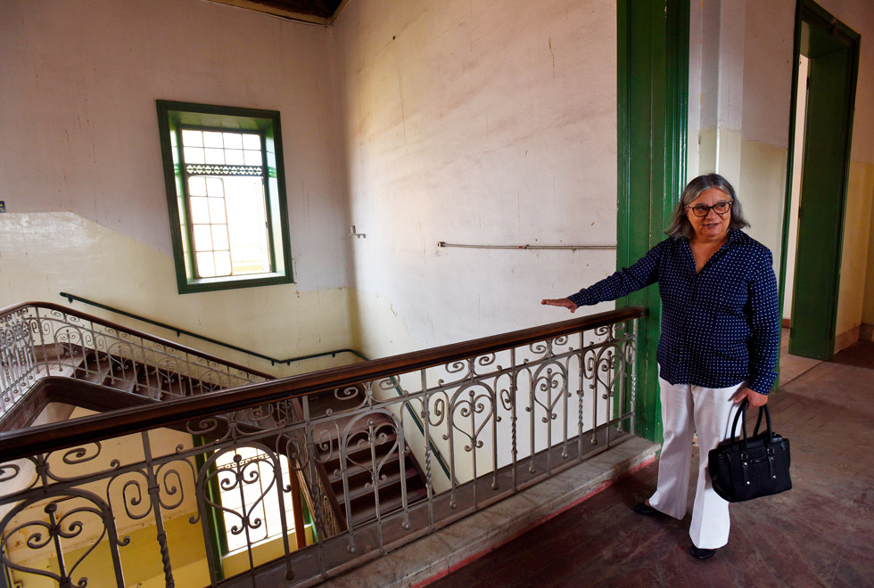 audiodecrição: fotografia colorida mostra coordenadora geral da unicamp, teresa atvars, dentro do prédio do Cotuca, ela está em pé apontando para detalhes da obra