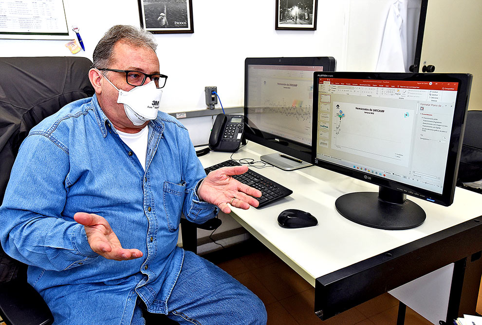 audiodescrição: fotografia colorida do diretor do serviço de coleta do hemocentro; ele está em escritório, em frente ao computador mostrando gráficos referentes às doações