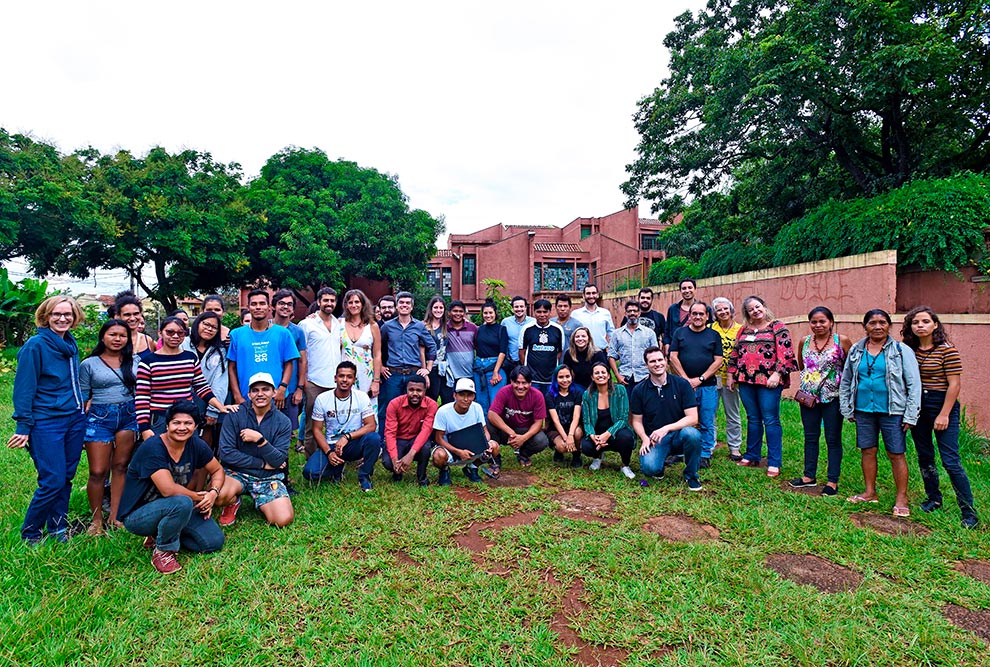 Audiodescrição: fotografia colorida mostra um grupo de cerca de 50 pessoas posando para fotografia em uma área externa da moradia estudantil da unicamp. Grande parte deles são estudantes indígenas.