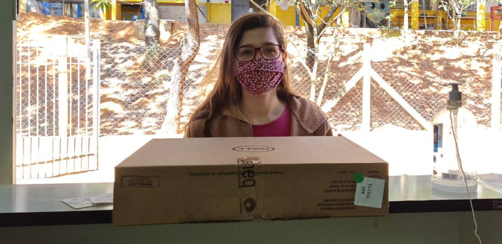 foto mostra eloise segurando uma caixa de laptop e usando máscara