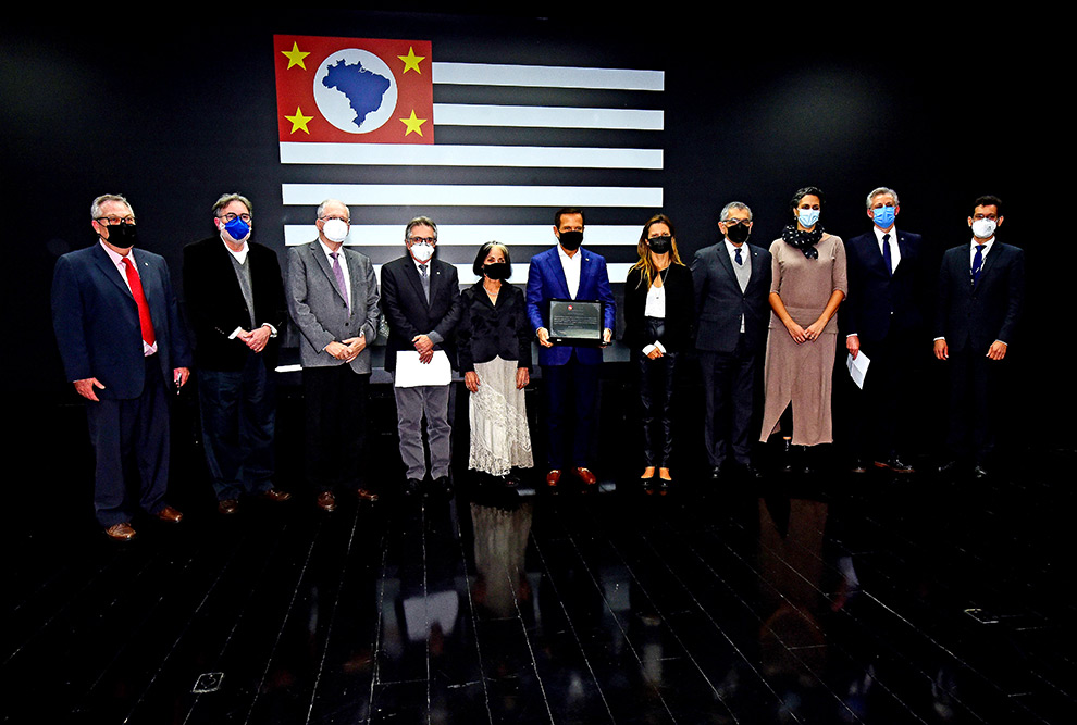 foto mostra governador dória, reitores das universidades e outros representantes posando para foto em frente a um painel com bandeira de são paulo